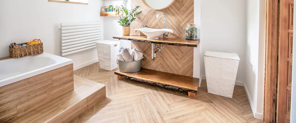 A unique bathroom vanity featuring a live-edge reclaimed wood countertop and matching shelves paired with a white vessel sink and wood-look herringbone wall tiles.