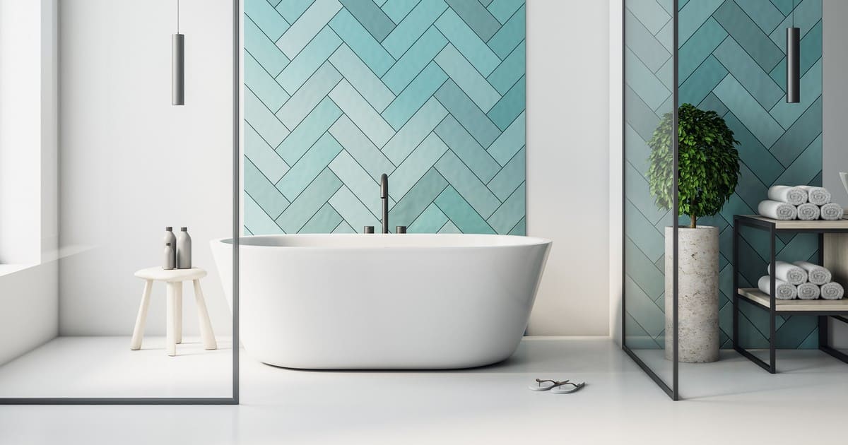A minimalist bathroom design showcasing a white freestanding bathtub against a teal herringbone tile accent wall, illustrating the success of following proper bathroom remodel steps.