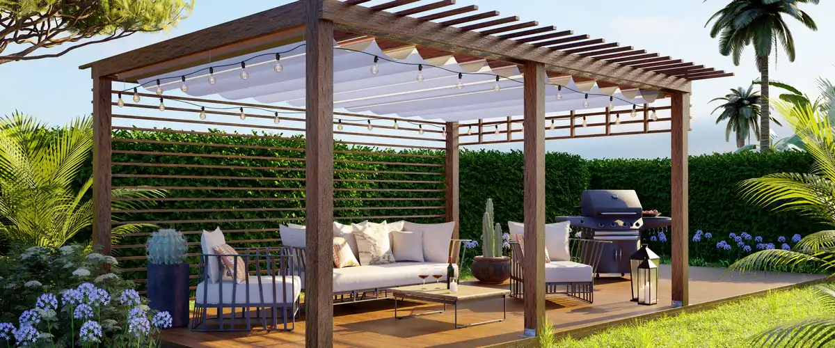 A freestanding dark wood pergola featuring a white retractable fabric shade and hanging string lights over a modern outdoor lounge and BBQ area.