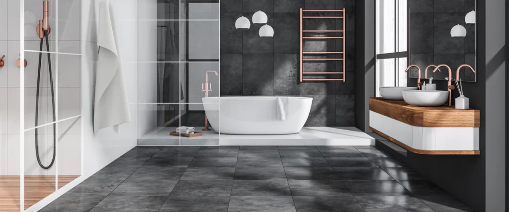 Modern bathroom materials featuring large-format dark grey wall tiles, a white tub, and luxury rose gold water fixtures.