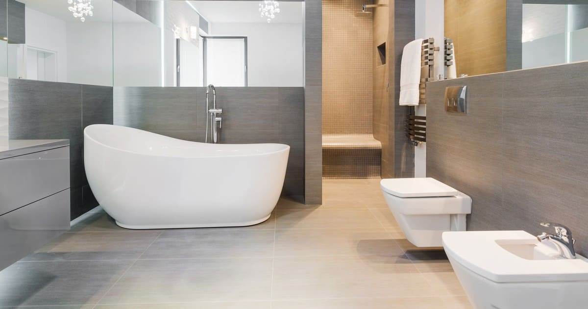 A spacious modern bathroom featuring a white freestanding bathtub and wall-mounted toilet, used as a guide for how to plan a bathroom remodel.