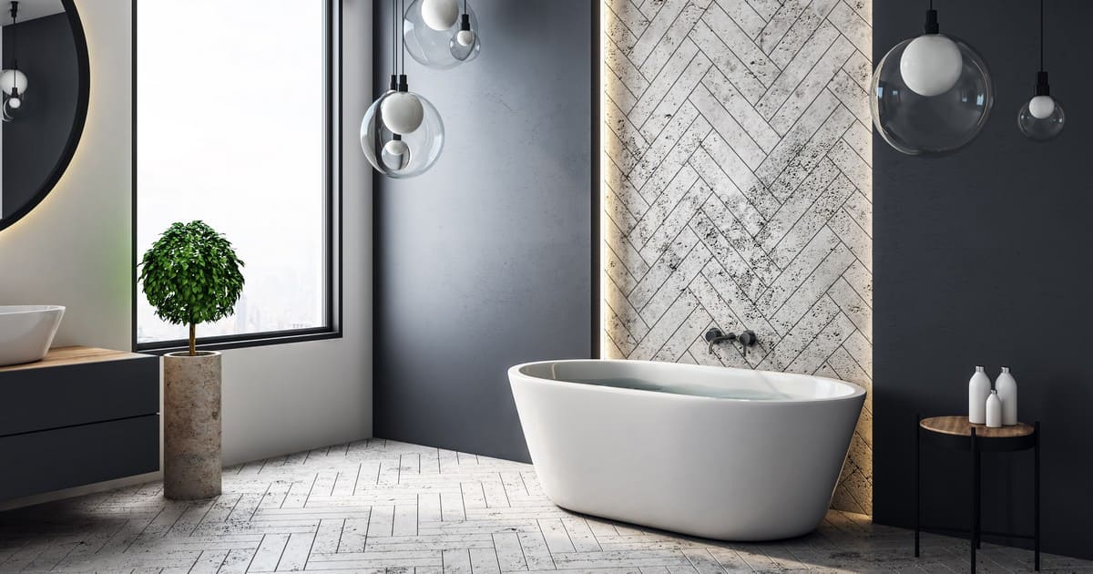 A conceptual luxury bathroom with a freestanding tub against a grey herringbone accent wall, illustrating the difference between a bathroom remodel vs renovation.