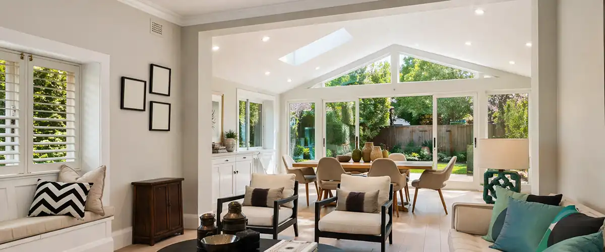 Open-concept home addition with living area, dining space, vaulted ceiling, and large backyard windows.