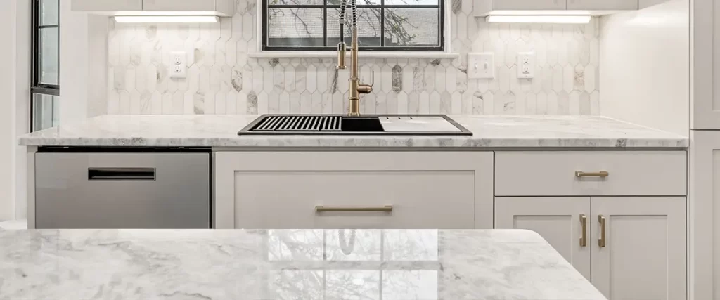 Luxury white kitchen remodel with marble countertops, hex tile backsplash, and brass hardware