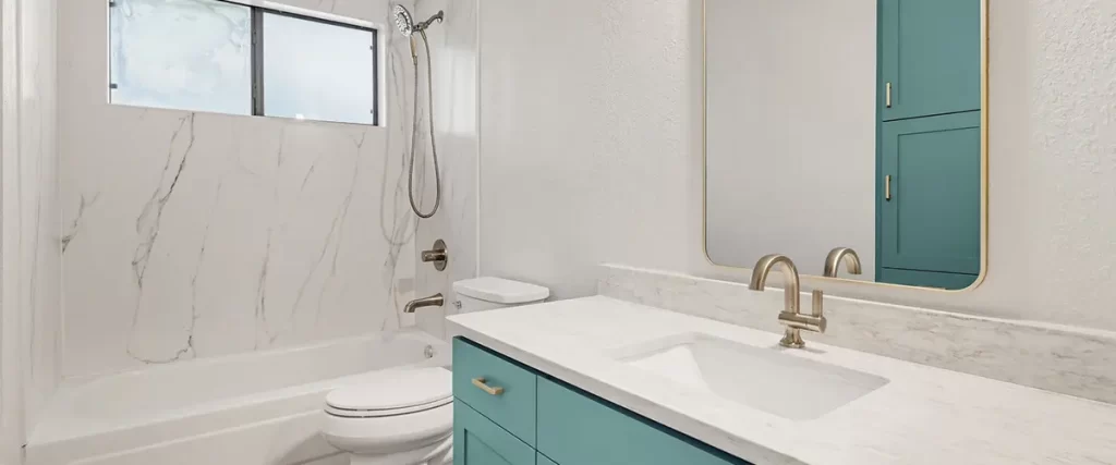 Modern bathroom remodel with blue vanity, marble shower walls, and brushed nickel fixtures
