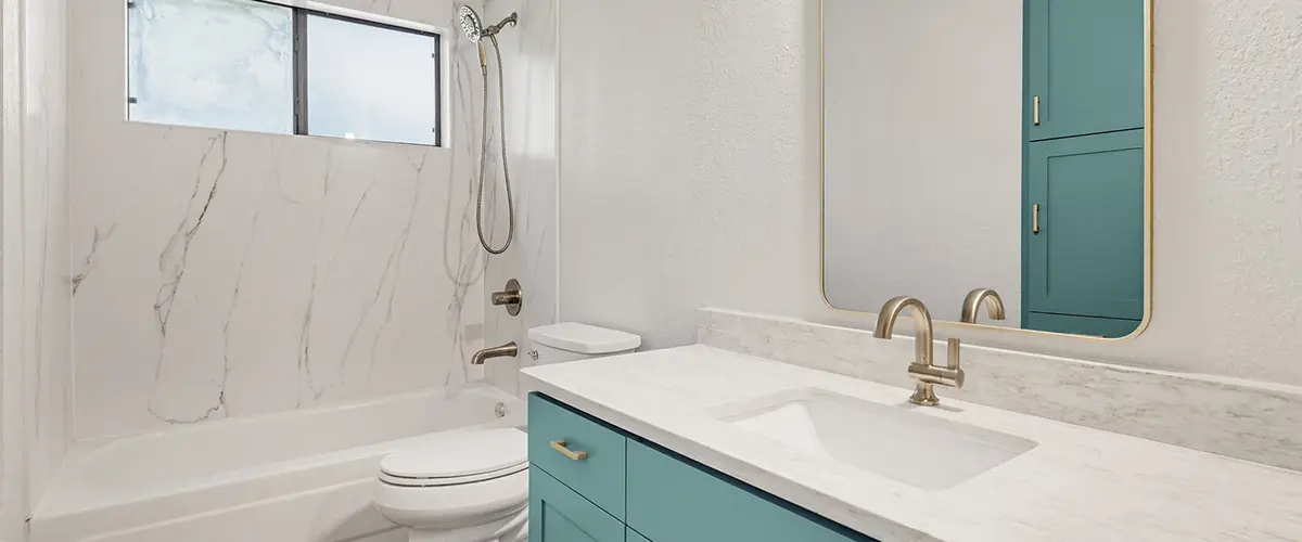 Modern bathroom remodel with blue vanity, marble shower walls, and brushed nickel fixtures