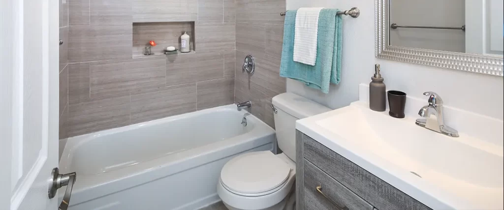 Contemporary bathroom renovation with tiled tub surround, custom vanity, and recessed shower niche