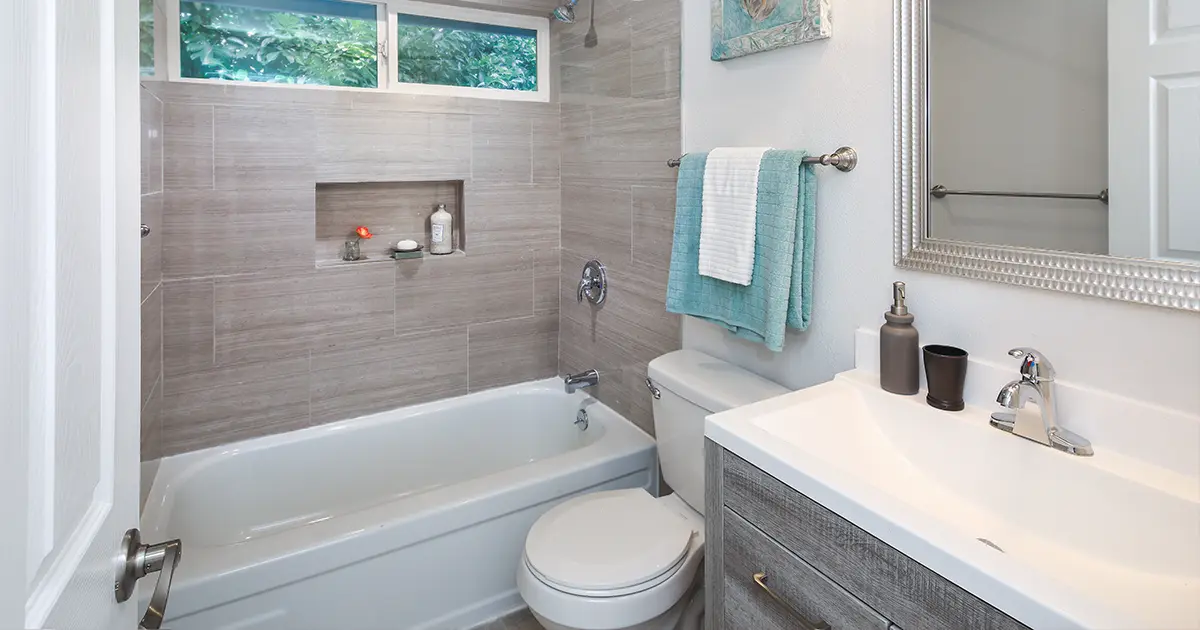 Contemporary bathroom renovation with tiled tub surround, custom vanity, and recessed shower niche