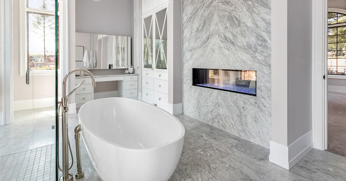 Luxury bathroom remodel with freestanding tub, marble feature wall, and built-in fireplace