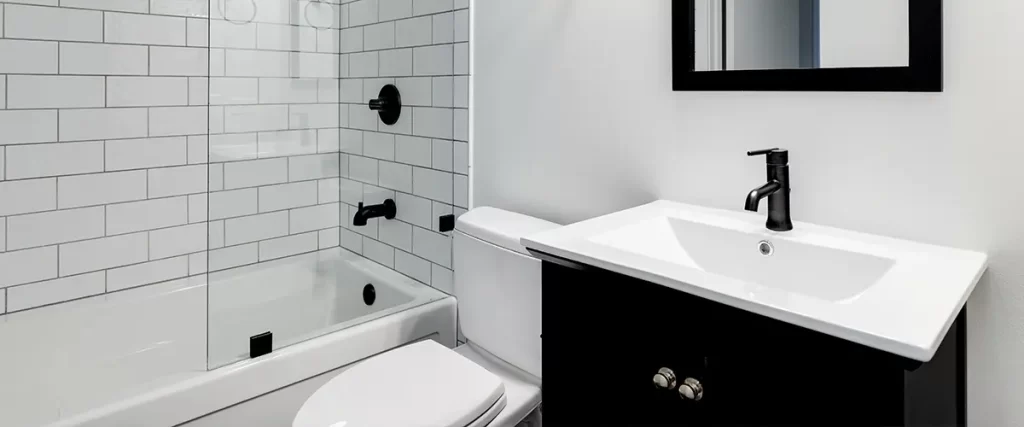 Modern bathroom remodel with white subway tile shower, glass enclosure, and black vanity fixtures