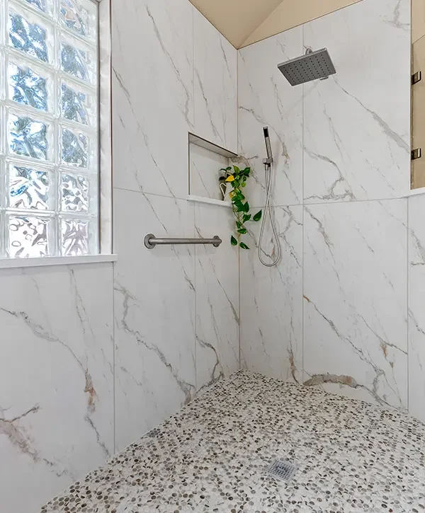 Walk-in shower conversion with marble-look tile, pebble floor, and rainfall showerhead