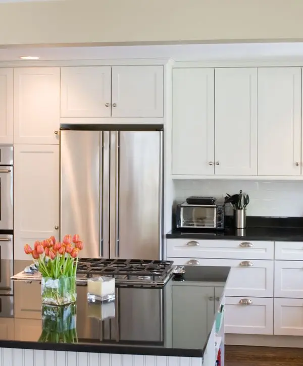Remodeled kitchen with white cabinets, modern counters, and warm flooring