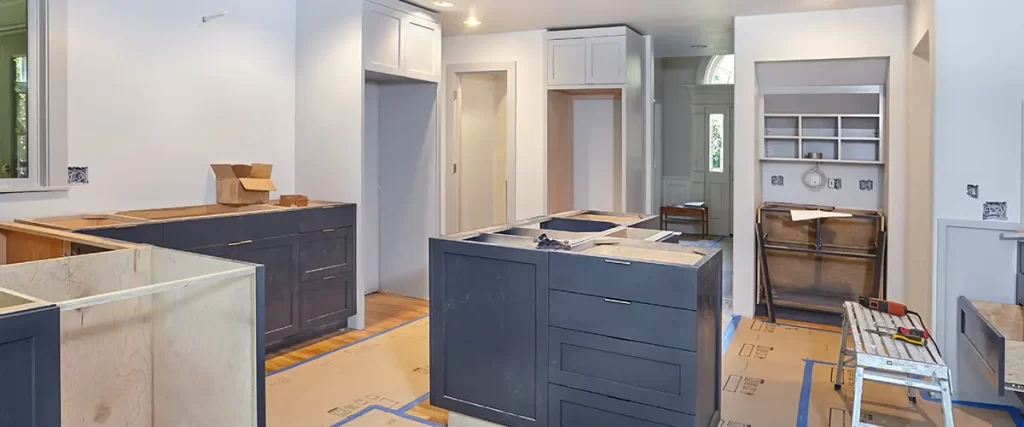 Kitchen renovation in progress with new cabinets, island installation and protected flooring